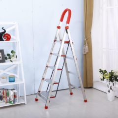 Silver aluminium step ladder with a red-capped handrail loop standing in a bright room beside white shelves