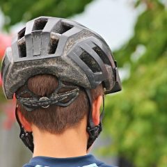 A grey mountain bike helmet seen from behind on a rider