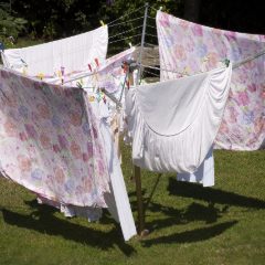 Floral and white bed linen pegged out on a rotary washing line on a sunny lawn