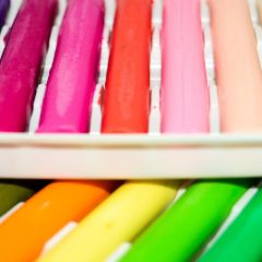 Rows of bright modelling clay bars in pink, red, orange, yellow and green lying in a white tray