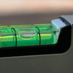 Close-up of a green bubble vial set in a dark grey metal spirit level