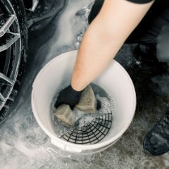 A sponge being dipped into a bucket of soapy water