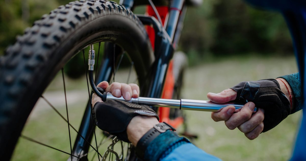 A rider pumping up a mountain bike tire with a hand pump