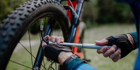 A rider pumping up a mountain bike tire with a hand pump