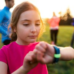 A girl checking the fitness band on her wrist in a sunny park