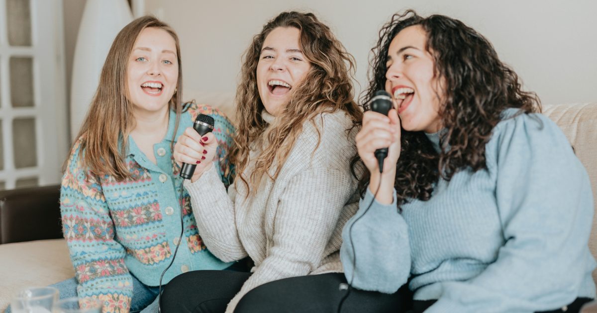 Friends singing into microphones at home