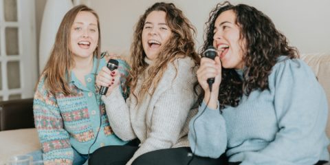 Friends singing into microphones at home