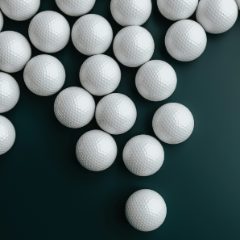 White golf balls scattered on a dark green background