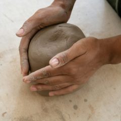 Hands shaping a ball of clay