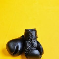 A pair of black boxing gloves on a yellow background