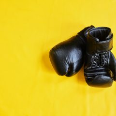 Black boxing gloves on a yellow background