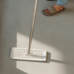 A white flat mop head gliding across a pale floor