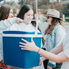 Friends carrying a blue cool box with a white handle
