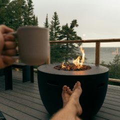 Feet up beside a round fire pit on a deck overlooking a lake