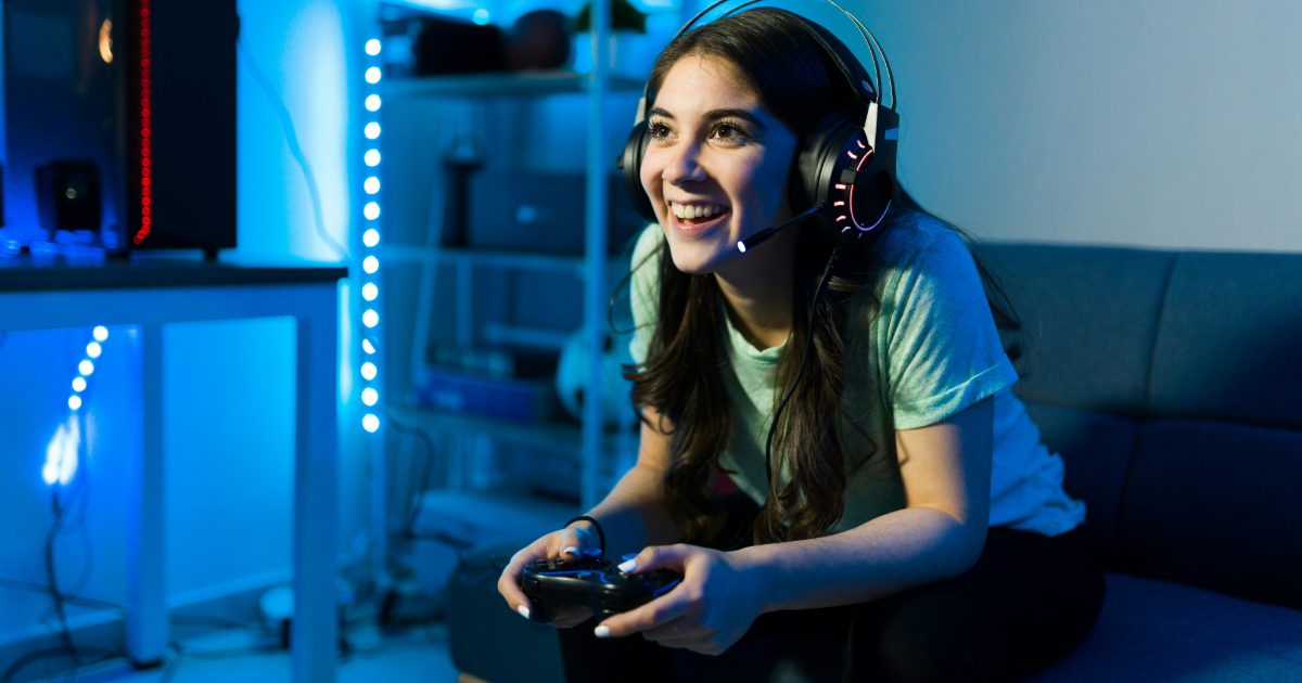 A smiling young woman gaming in a headset
