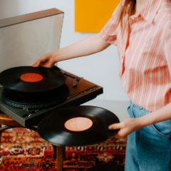 A woman putting red-label records on a wooden turntable with a clear lid