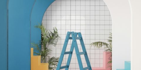 A blue step ladder in a bright room with arches, tiles and plants