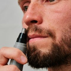 A bearded man using a slim nose trimmer