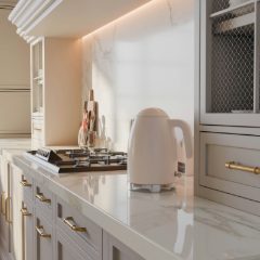 Cream retro kettle with a domed lid and chrome base on a white marble worktop in a soft cream kitchen