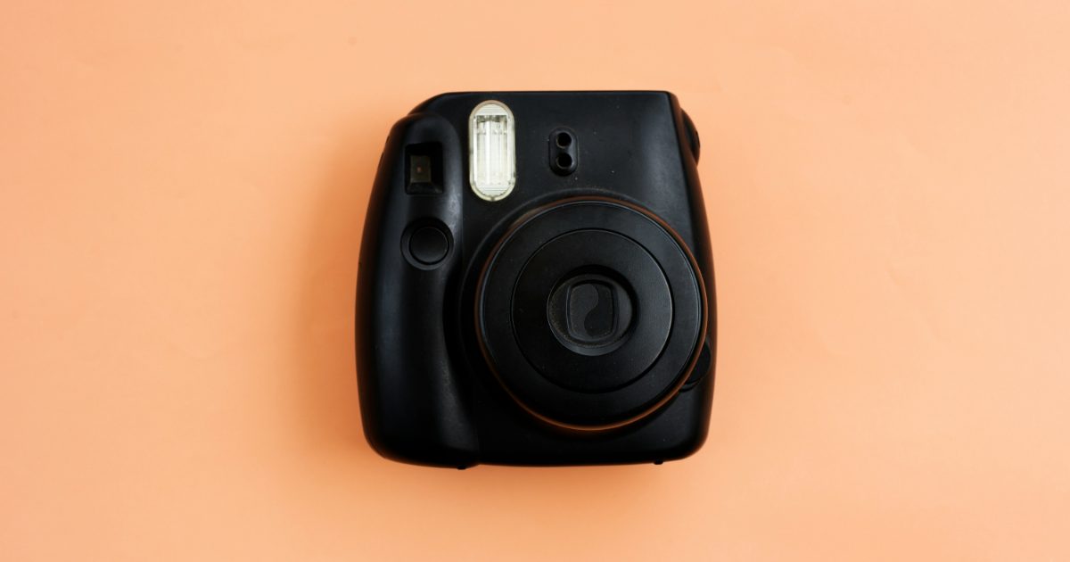 A black instant camera on a peach background