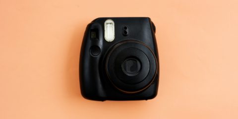 A black instant camera on a peach background