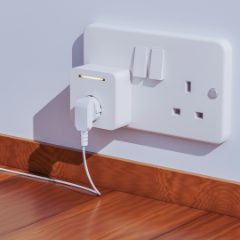 A white smart plug with a small light in a double wall socket, a lead plugged into it