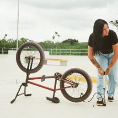 A woman using a silver floor pump on a bike tyre in a skate park
