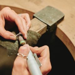 Hands polishing a ring with a slim pale grey rotary tool