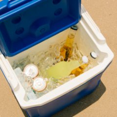 A blue and white cool box full of ice and drinks