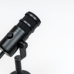 A black dynamic microphone with a volume knob on a desk stand