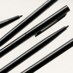 Several black fine pens laid out on a white surface