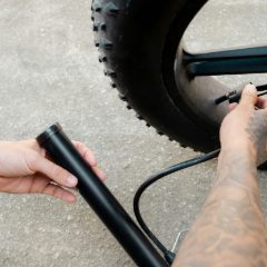 Hands inflating a bike tyre with a black mini pump