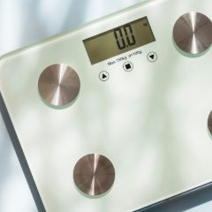 A glass smart scale with four metal pads and a digital display