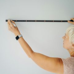 A woman marking a white wall with a long ruler