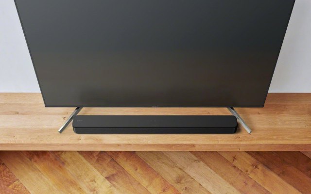 Sony HT-SF150 soundbar in front of a TV on a wooden stand