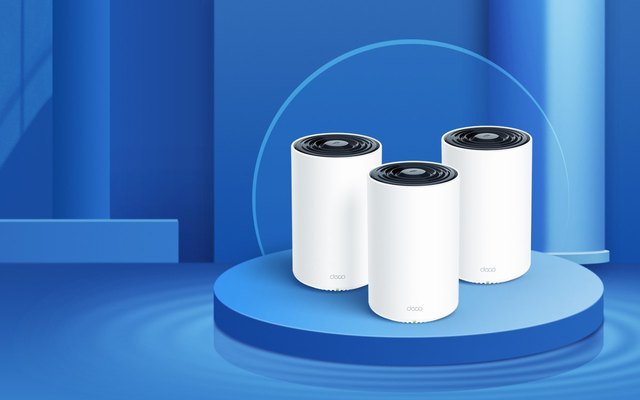 Three white TP-Link Deco XE75 mesh Wi-Fi units standing on a round blue platform