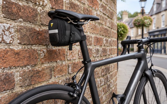 Topeak Aero Wedge saddle bag, strapped under the saddle of a road bike leaning against an old brick wall in a British market town
