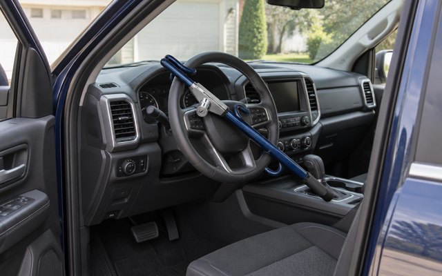 The Club 1102 LX, inside a parked pickup truck, seen through the open driver's door in a driveway