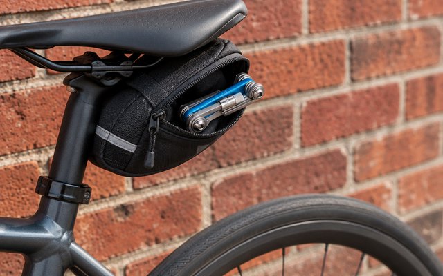 Park Tool IB-2 multi-tool, half out of a saddle bag on a bike by a red-brick wall