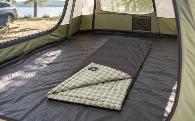 Coleman Heritage Big & Tall sleeping bag, unrolled inside a roomy family tent at a car campsite, the flannel lining showing at the open corner