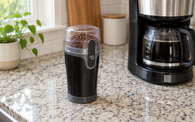 Hamilton Beach Fresh Grind grinder, on a speckled granite counter beside a drip coffee maker in a suburban kitchen