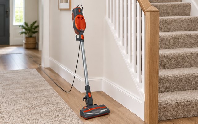 Shark Rocket stick vacuum, standing at the foot of carpeted stairs in a townhouse hallway