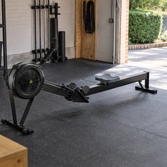 Concept2 RowErg, in a British garage turned home gym, with a rubber floor mat and the garage door open to daylight
