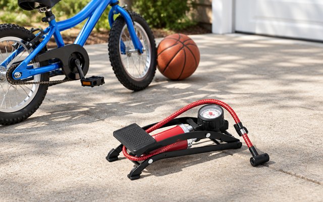 Franklin Sports foot pump, on a sunny driveway beside a basketball and a kid's bike