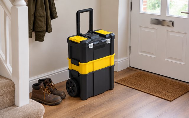 Black and yellow three-tier rolling toolbox with its handle up, in a hallway by the front door