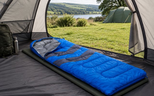MalloMe 3-season sleeping bag, unzipped a little and laid out on a camping mat inside a tent, the tent door open onto a green campsite