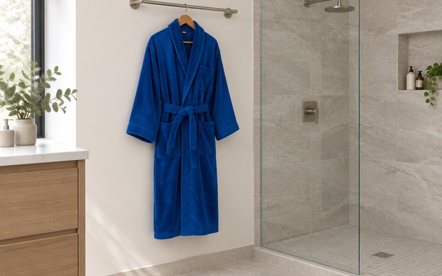 Alpine Swiss terry velour robe, on a wooden hanger hanging from a towel bar beside a walk-in shower