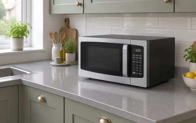 Toshiba 23L microwave, on a grey quartz worktop in a modern British kitchen with sage green cabinets
