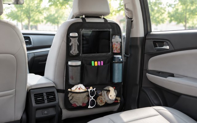 ULEEKA backseat organizer, strapped to the back of the passenger seat in a sedan, a tablet with its screen off in the clear pocket