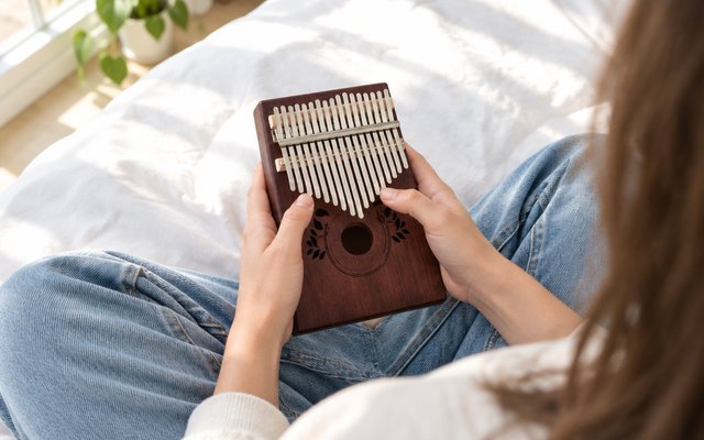 UNOKKI mahogany kalimba, played by a teen on a bed
